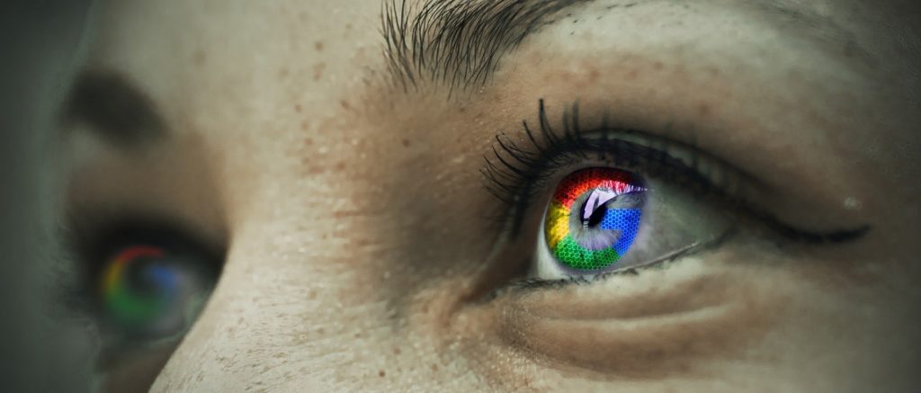 Fokus auf die Augenpartie einer weiblichen Person, mit Spiegelung von Google-Logo auf der Linse